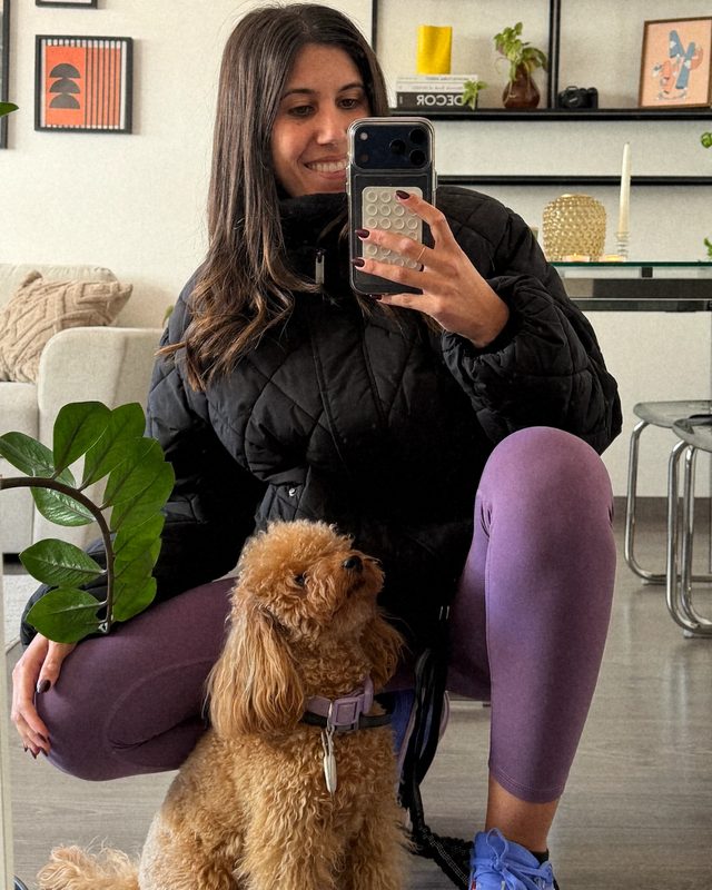 Diana agachada haciéndose una foto en el espejo de casa con Croqueta, su perrita de pelo rizado color canela